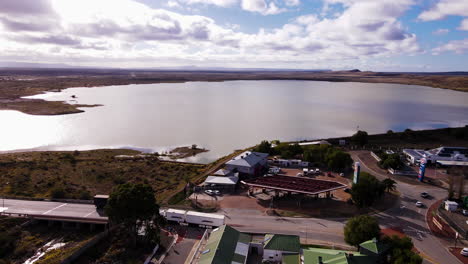 Freight-trucks-on-highway-entering-and-exiting-Beaufort-West,-view-of-dam