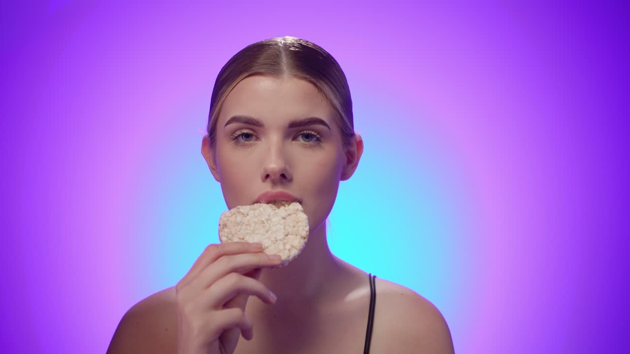 modelo de fitness muerde en un pastel de arroz blanco, dieta vegana, toma de estudio