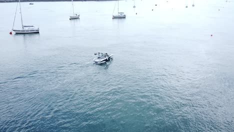 Leisure-motor-boat-aerial-view-navigating-quiet-river-Conwy-harbour-marina-between-yachts