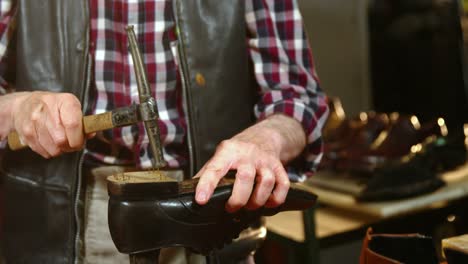 shoemaker hammering on a shoe in workshop