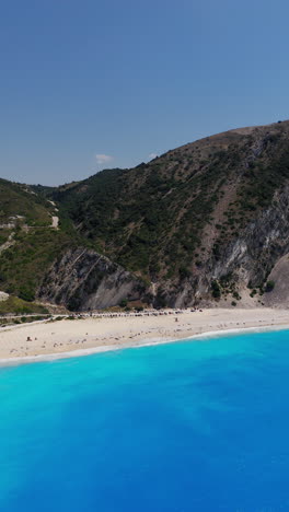 panoramic aerial view of myrtos beach with limestone cliffs on backdrop, kefalonia island, ionian sea, vertical