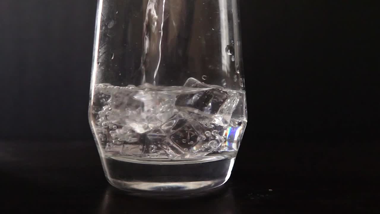 얼음에 쏟아지는 물의 슬로우 모션을 닫습니다