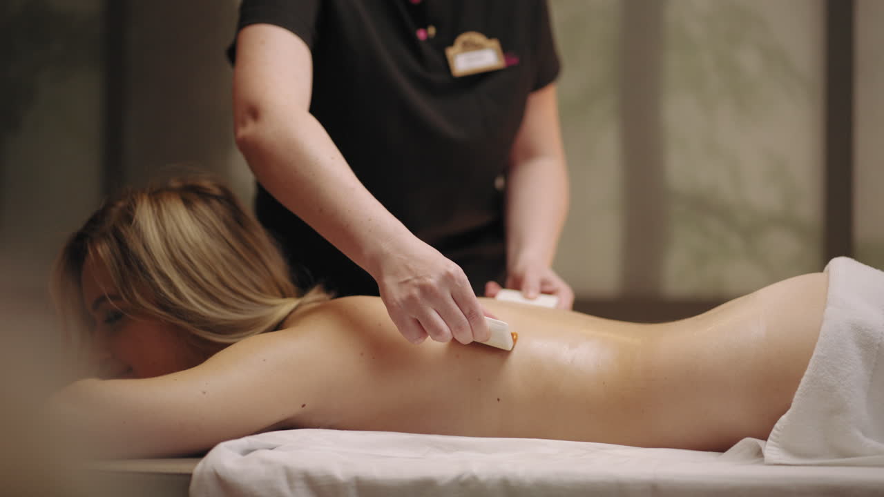 tratamiento de relajación en el salón de masajes masajista está acariciando la espalda de la paciente femenina con pinceles suaves