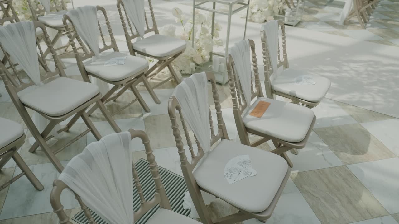 Soft white wedding chairs arranged neatly in a bright ceremony space