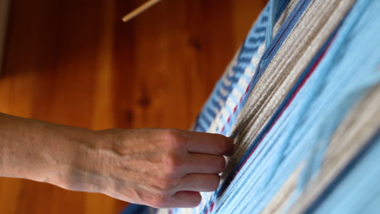 Hands Weaving with Weaving Needle on Loom with Blue and Beige Yarn