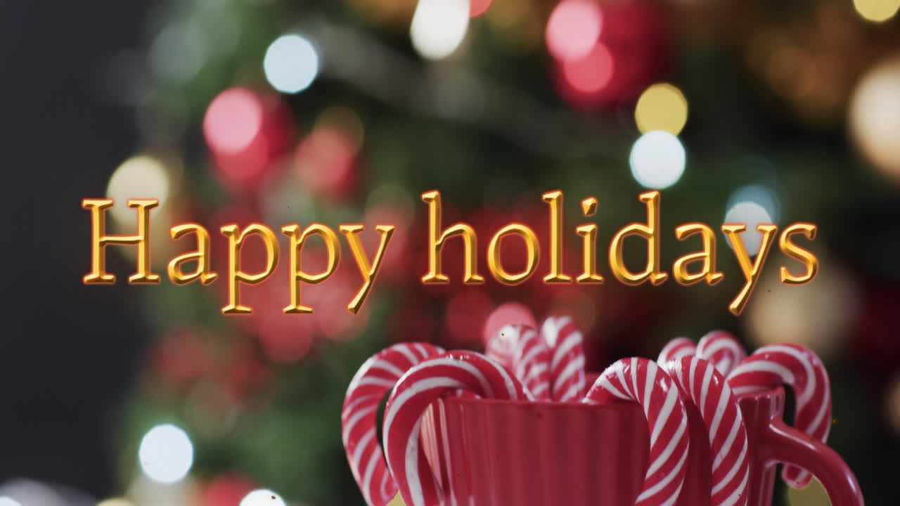 Happy holidays text in orange with candy canes and defocused christmas tree with lights
