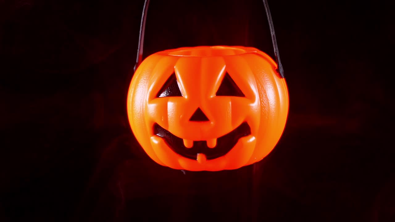 concepto de halloween - moviendo linterna de calabaza de plástico con humo blanco alrededor aislado en fondo negro oscuro, aterrador y estado de ánimo de horror.