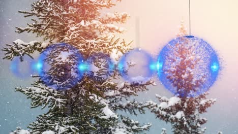 animation of snow falling over christmas baubles in winter landscape