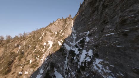 FPV-Drohne-Fliegt-Bei-Sonnenuntergang-Durch-Einen-Gefrorenen-Wasserfall-In-Den-österreichischen-Bergen