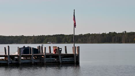 view of dock on calm lake with american flag