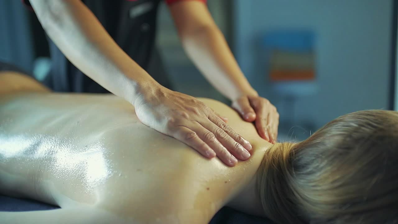 masajista masajea la espalda de la chica con aceite de masaje