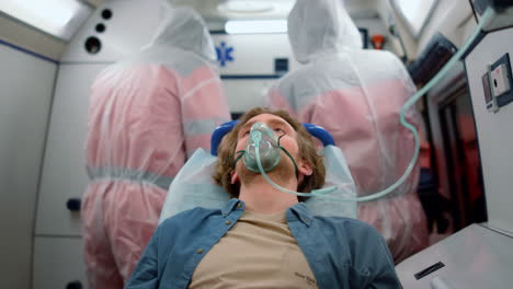 Man-sitting-on-stretchers-in-emergency-vehicle.-Victim-breathing-in-oxygen-mask