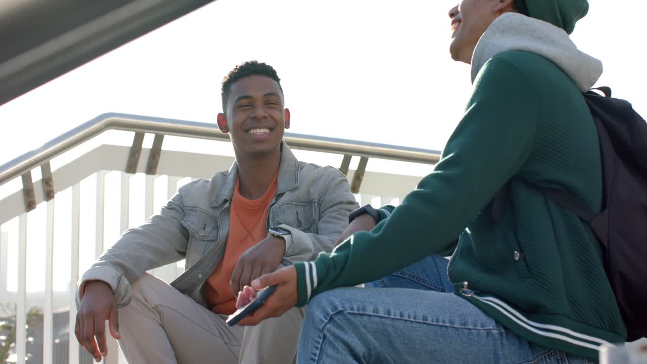 Lifting smartphone from pocket, Diverse male friends sharing laughter viewing screen on bleachers