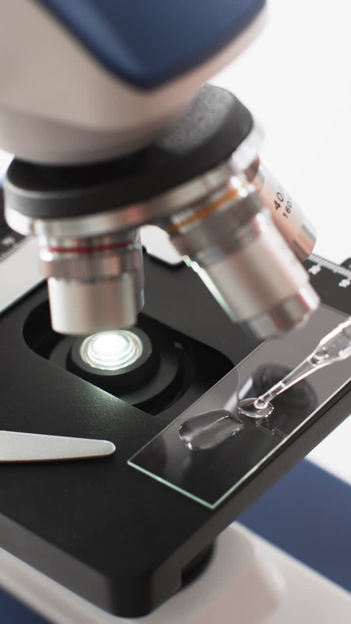 Vertical video of close up of laboratory microscope with copy space on white background