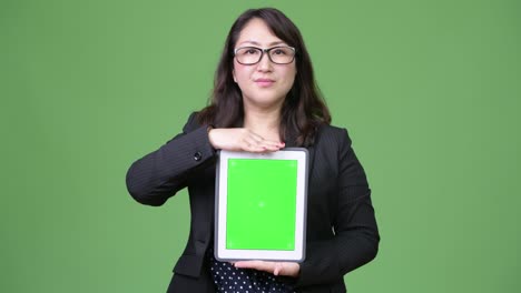 una hermosa mujer de negocios asiática madura mostrando una tableta digital