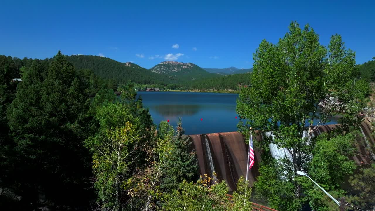 Evergreen Lake House Park and Rec Center Golf Course Keys on the green downtown mountain town summer sunny blue sky flag water dam Colorado aerial drone circle right slowly motion