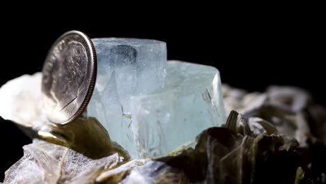 a tight detail shot of an aquamarine crystal in a muscovite matrix using a dime as a reference for size