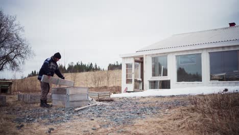 the man is moving the collapsible materials next to the storage house required for building the diy hot tub - static shot