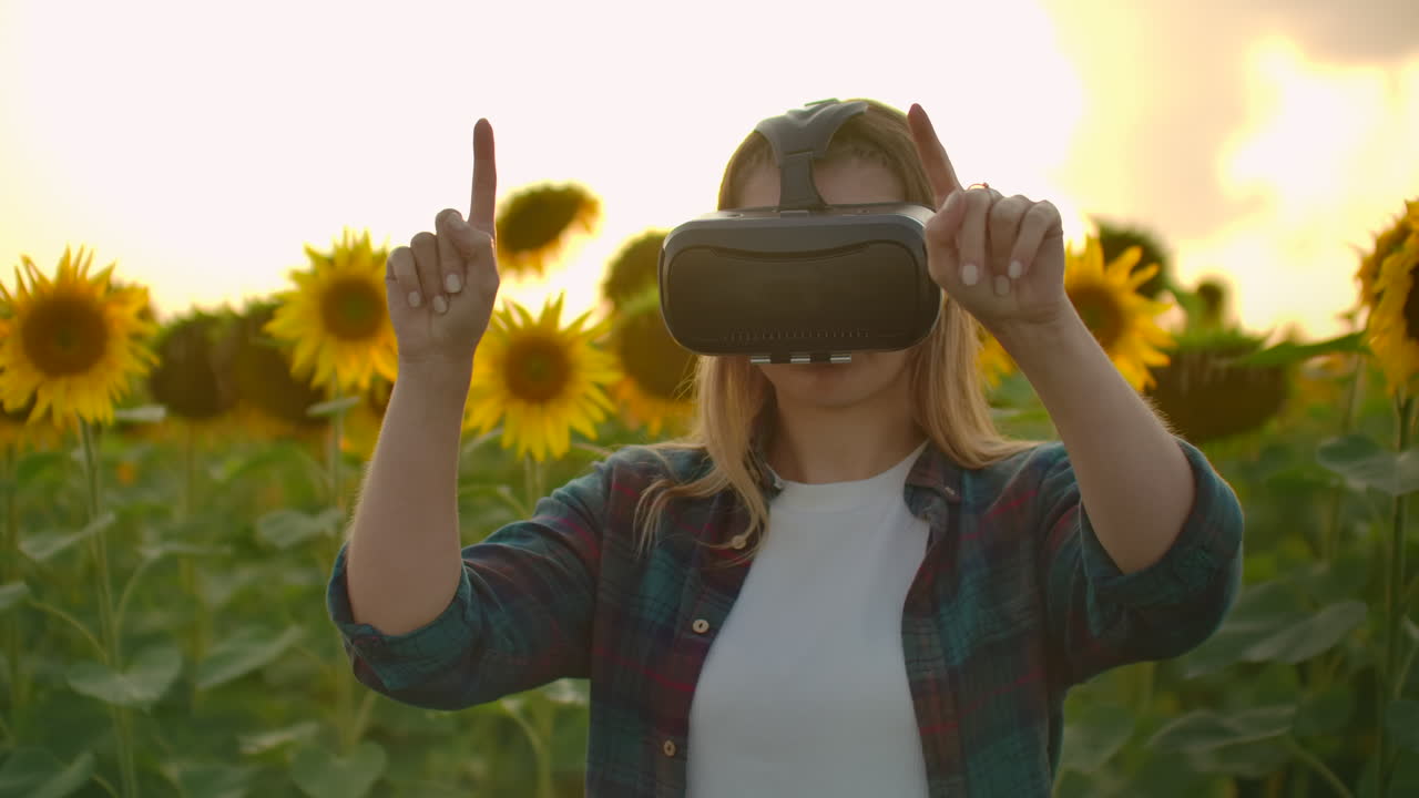 la chica está trabajando en gafas vr. está involucrada en el proceso de trabajo. es un día soleado perfecto en el campo de girasoles.