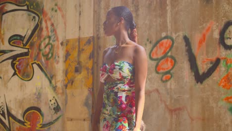 a young woman stands next to grafitti on a wall in an abandoned warehouse