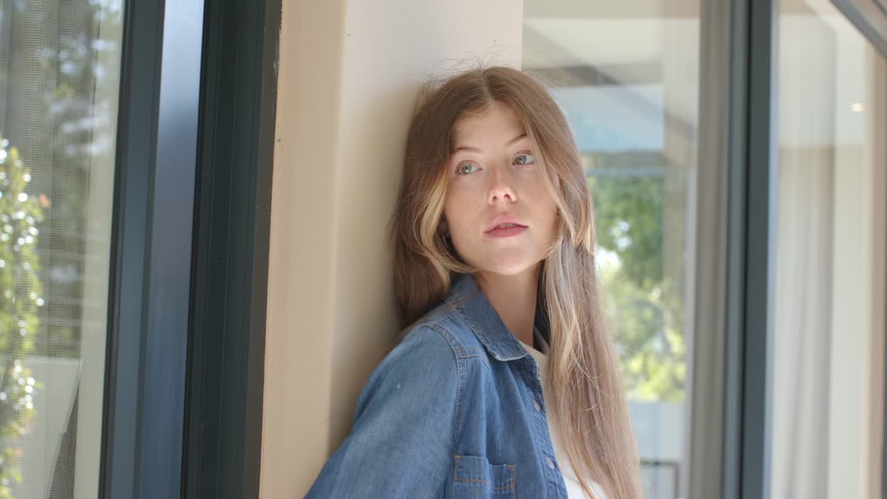 Kvinde i denimjakke læner sig op ad en beige søjle ved en glasrude, kameraet zoomer ind og får hendes blik til at skifte.