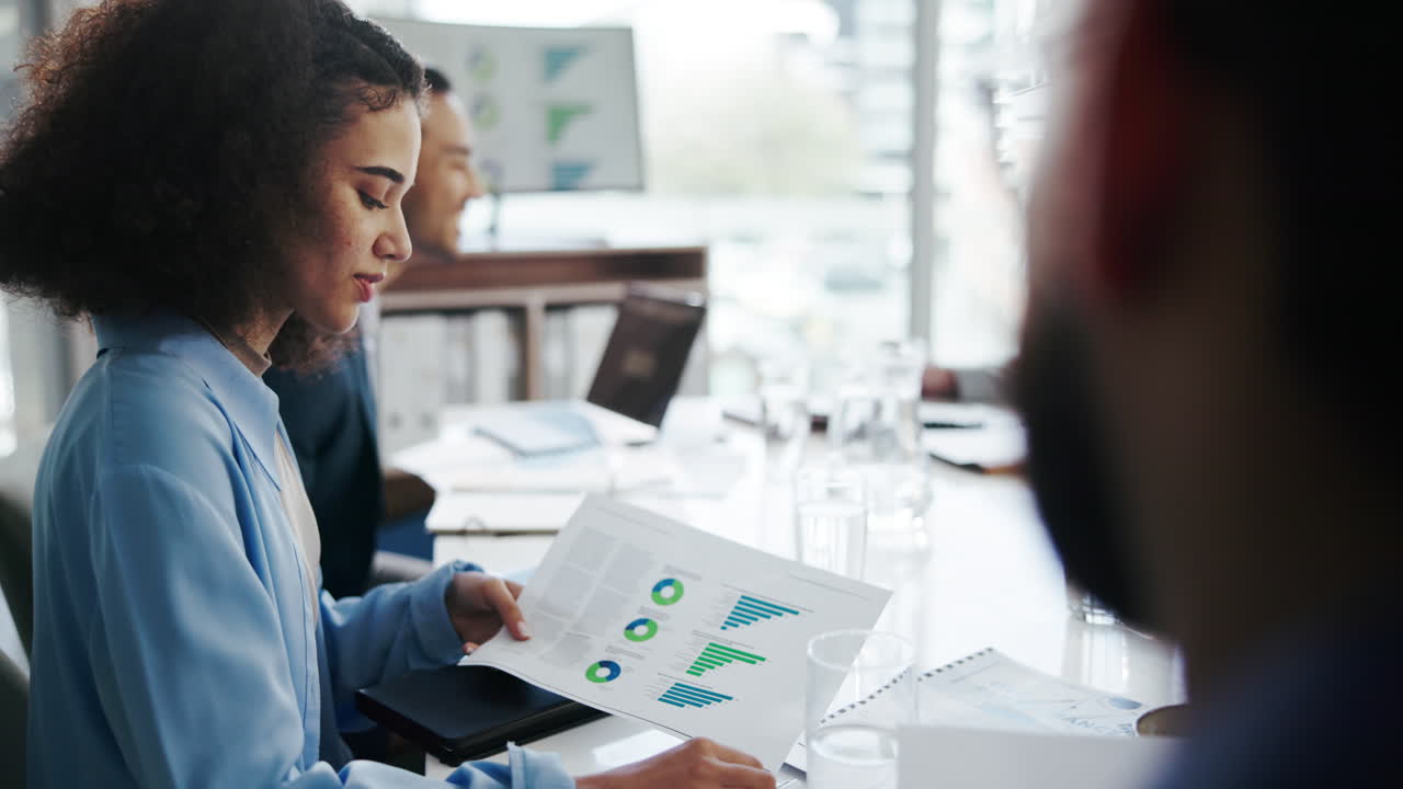 una reunión de negocios en una oficina con una mujer presentando gráficos y datos a un grupo de personas.