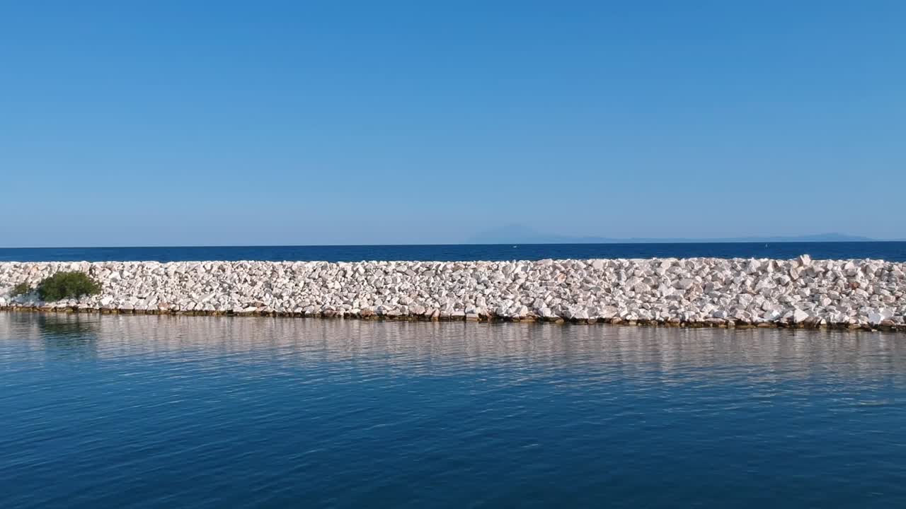 toma constante de un puerto tranquilo al lado de un rompeolas con vista al océano en kavala, grecia