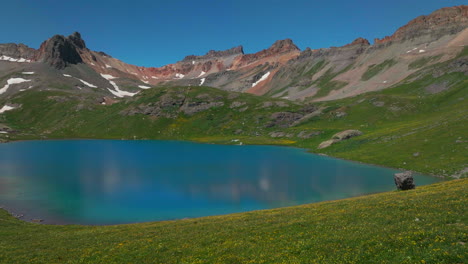 aerial drone cinematic deep sky blue stunning ice lake basin island lake silverton colorado stunning heavenly very green summer wildflower rocky mountains snow melting telluride 14er peaks circling