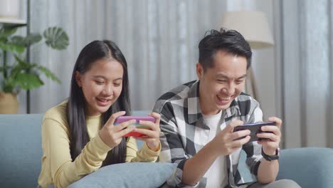 couple playing games on smartphones at home