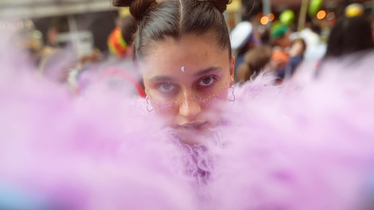 Giovane donna felice con make-up glitterato e un boa rosa a un festival
