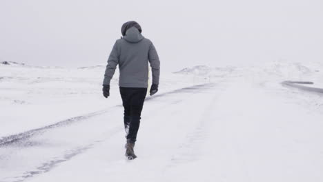 young male traveler walking through blizzard in slow motion