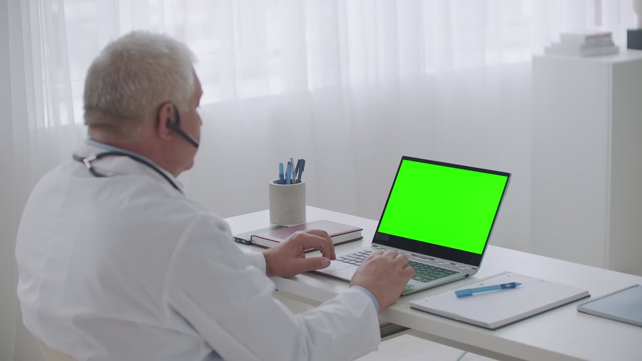 conferencia médica en línea, médico masculino está viendo y escuchando webinar en portátil con pantalla verde para tecnología de clave de croma, modo de trabajo remoto