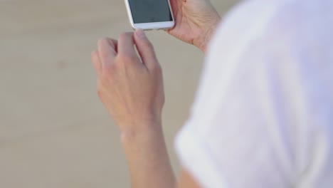 Focused-middle-aged-brunette-using-smartphone-outdoor.