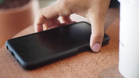 person using smartphone at a wooden table in a cafe