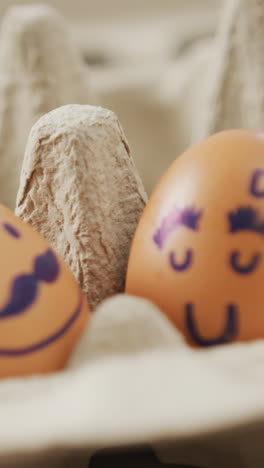 video de primer plano de dos huevos marrones con caras dibujadas en el fondo de un cartón de huevos