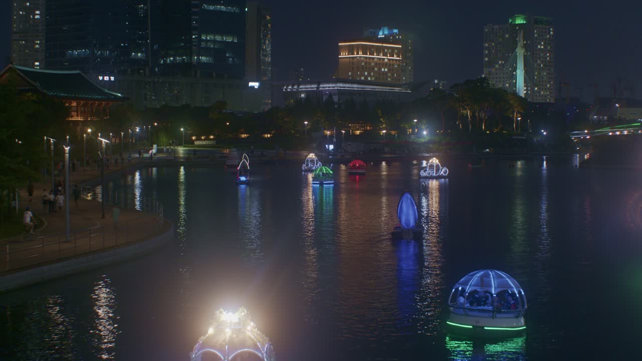 hermosa vista romántica del parque nocturno con el río en la ciudad luces de la ciudad y barcos vista de alto ángulo desde el puente