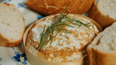 panning over baked french camembert with rosemary and baguette bread