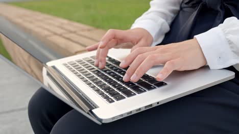 focused businessperson: slow motion close-up hand typing on laptop keyboard outdoors