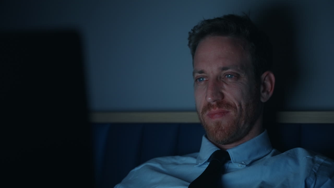 늦은 밤 노트북에서 일하는 남자, 화면의 빛에 의해 조명 된 얼굴