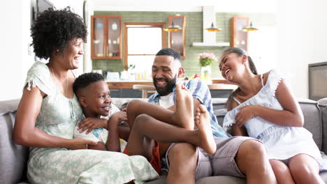 Happy-african-american-parents,-daughter-and-son-having-fun-on-sofa-in-living-room,-slow-motion