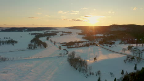 picturesque winter aerial flying over a frozen, snow covered landscape at sunset