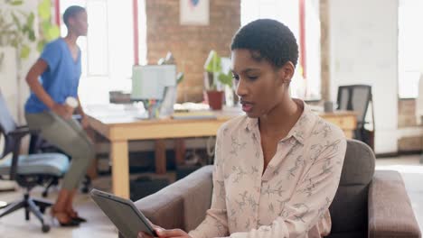 Happy-african-american-colleagues-using-tablet-and-walking-in-office,-slow-motion