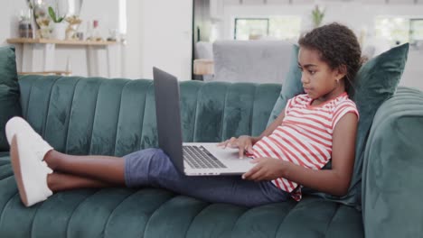 Feliz-Chica-Afroamericana-Sentada-En-El-Sofá,-Usando-Laptop,-Cámara-Lenta