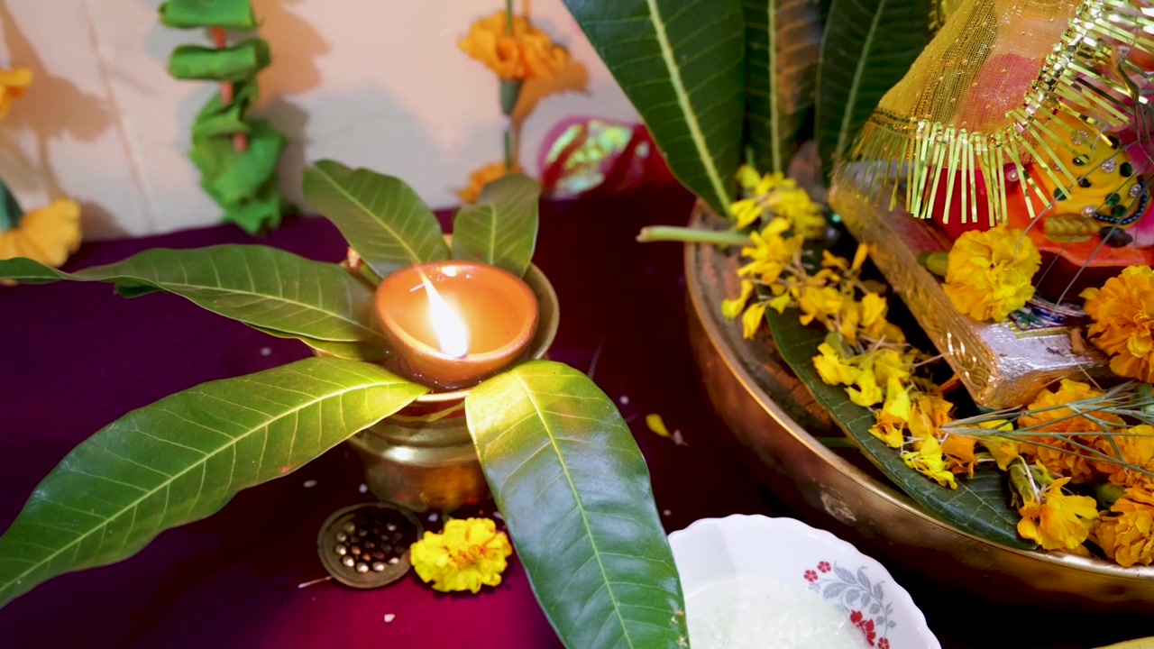 Allestimento tradizionale di puja indù con lampada a olio accesa, sacro kalash e decorazioni floreali sacre.