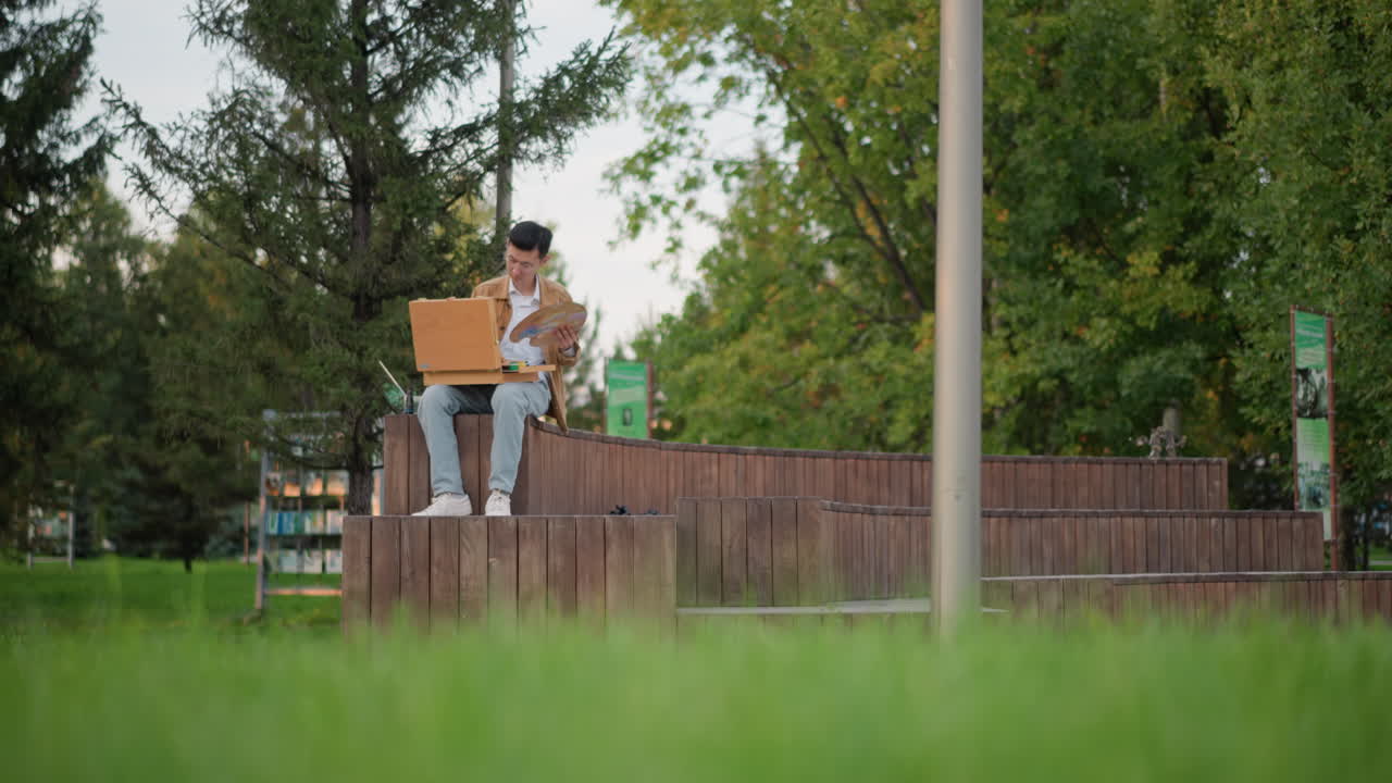jovem sentado em um banco de madeira com laptop e mochila, freelancer remoto escrevendo código e estudando ao ar livre, árvores verdes e plano de fundo com grama, jaqueta casual, digitando concentrado, atmosfera diurna relaxante