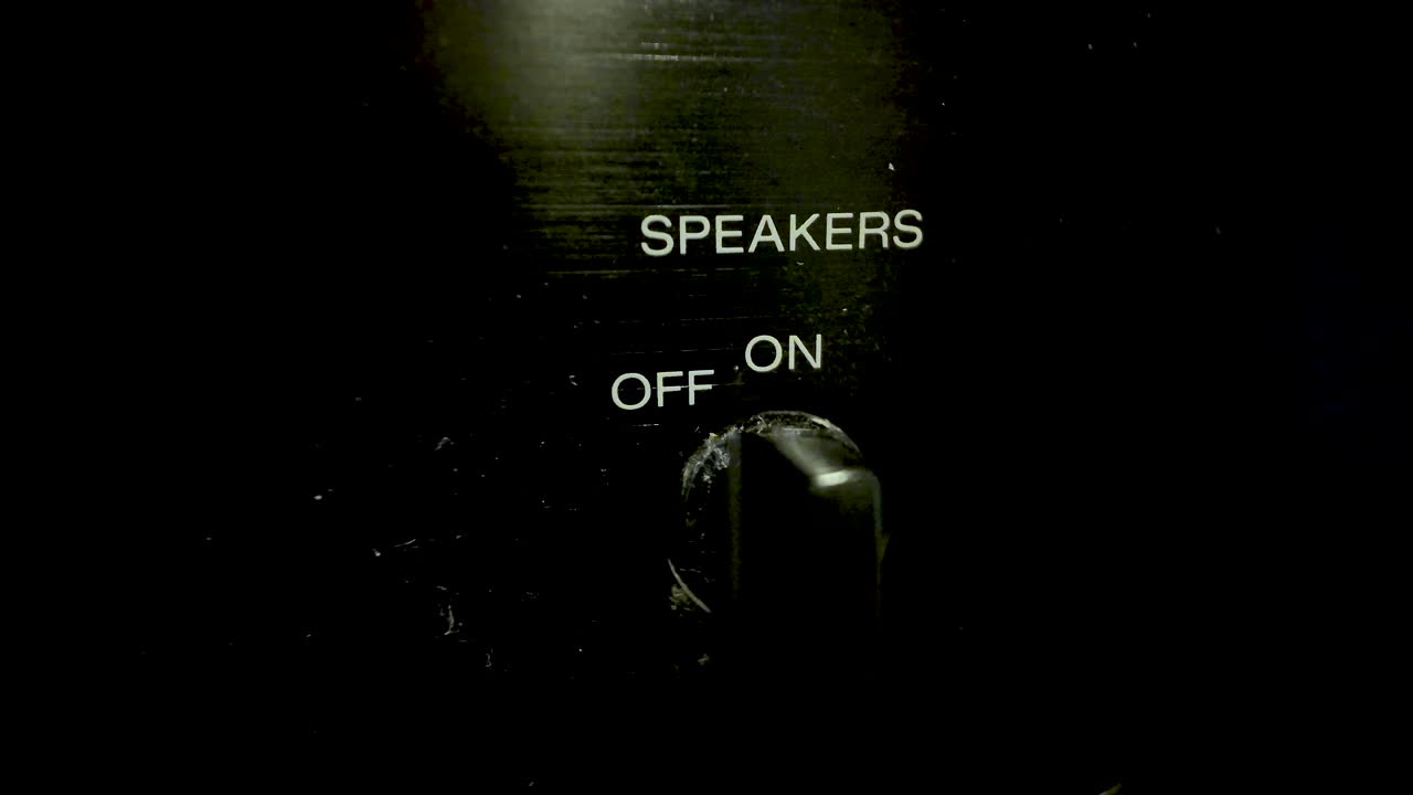 Close-up of a volume knob on a black hi-fi amplifier, showing speaker on off labels