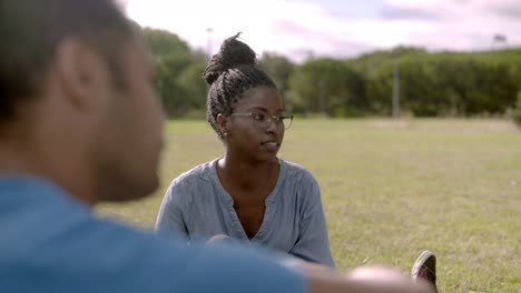 smiling african american woman talking with friends on lawn