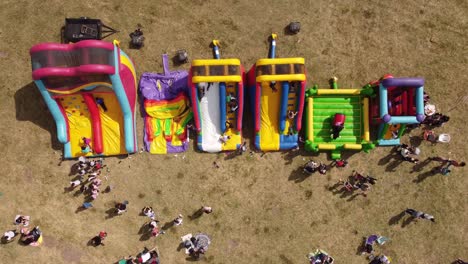 Aerial-time-lapse-shot-of-kids-having-fun-outdoors-on-inflatable-bouncer-castle-in-sunlight