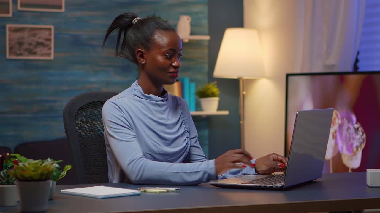 Black woman typing on computer and writing on stick notes