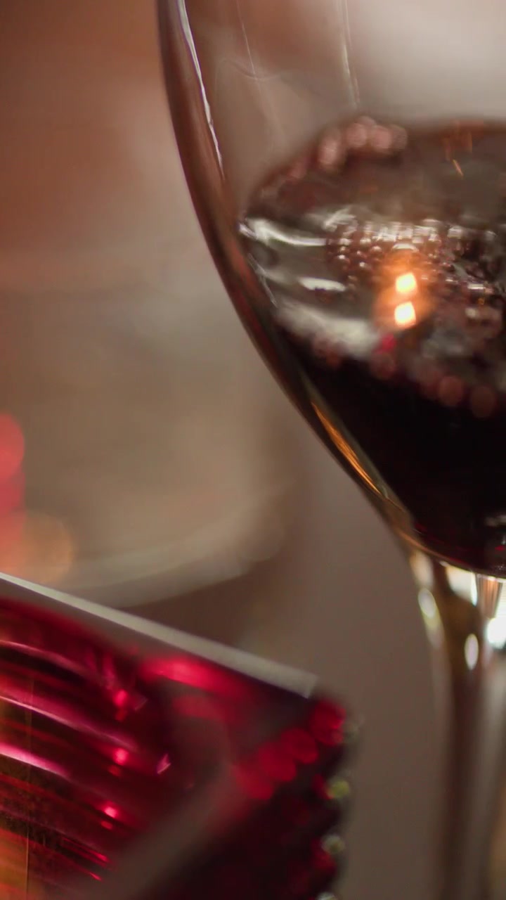 Close-up de vinho tinto sendo derramado em uma taça, ambiente acolhedor de restaurante à luz de velas, profundidade de campo rasa.